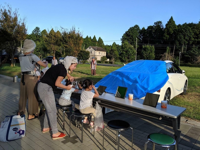 千葉県山武市の避難所に運ばれてきた電動車から電気を供給し、10日ぶりにドライヤーを使えたという被災者たち（筆者撮影）